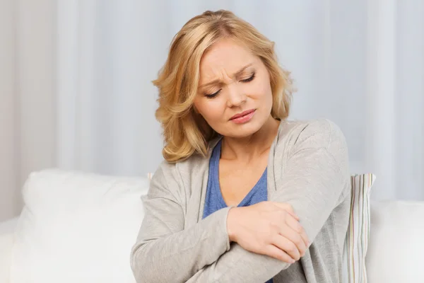 Unhappy woman suffering from pain in hand at home