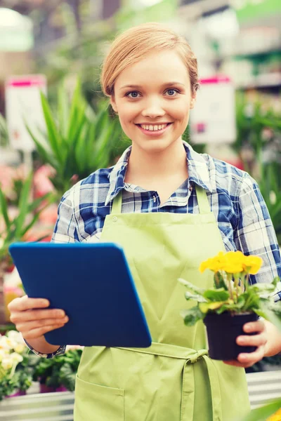 Happy woman with tablet pc in greenhouse