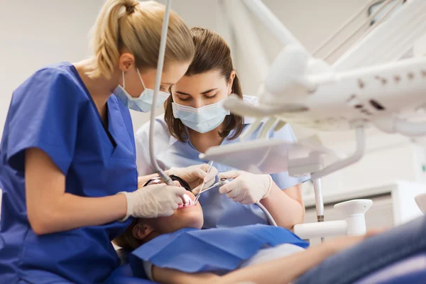 Female dentists treating patient girl teeth