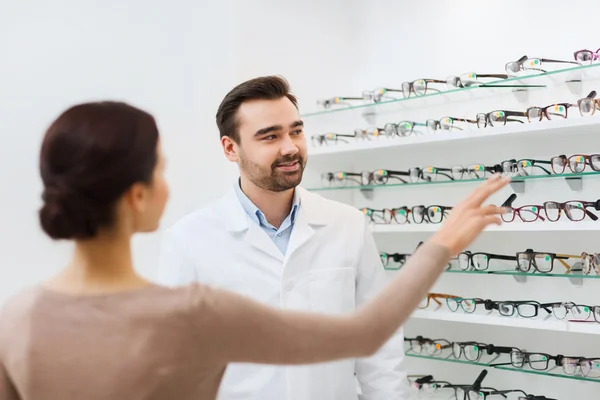 Woman showing glasses to optician at optics store