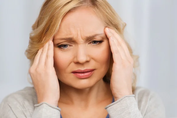 Unhappy woman suffering from headache at home