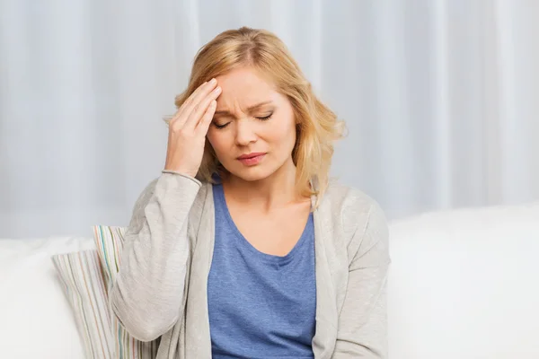 Unhappy woman suffering from headache at home