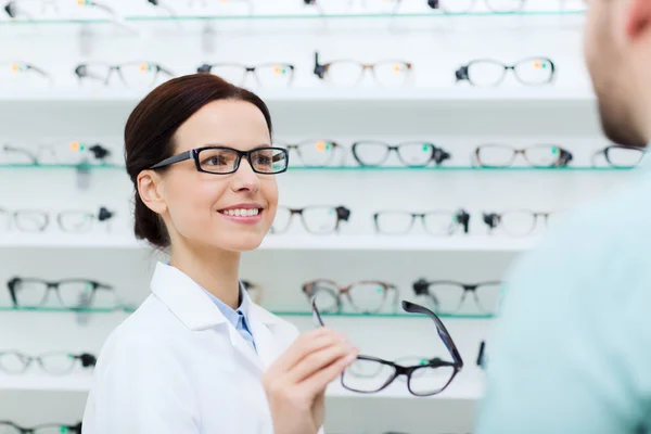 Optician showing glasses to man at optics store