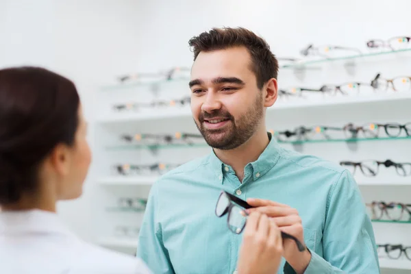 Optician showing glasses to man at optics store