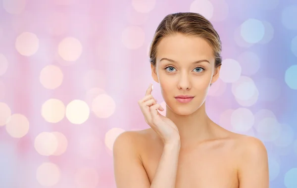 Young woman applying cream to her face