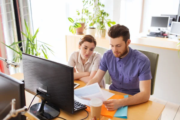 Creative team with computer and papers in office