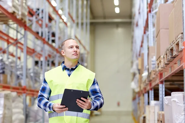 Man with clipboard in safety vest at warehouse