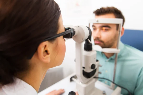 Optician with slit lamp and patient at eye clinic