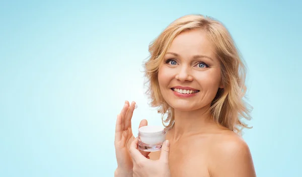 Happy woman applying cream to her face