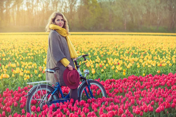 Female riding her bike through tulip fields