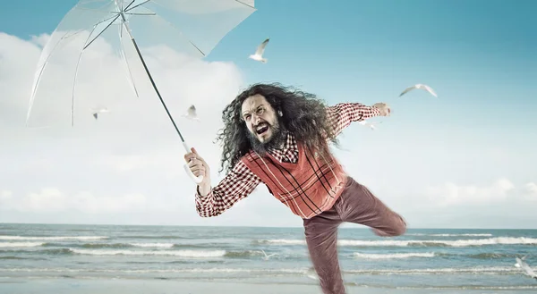 Funny guy holding an umbrella on a beach