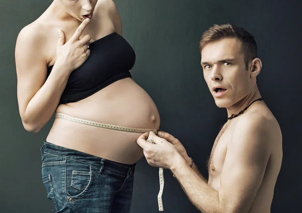 Happy parents measuring on pregnant woman's belly