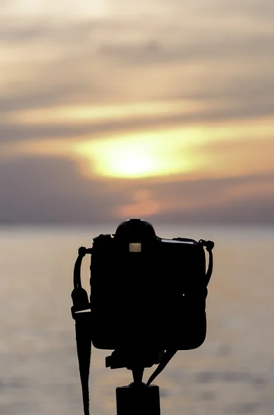 Silhouette of Digital camera beside sea at sunset time