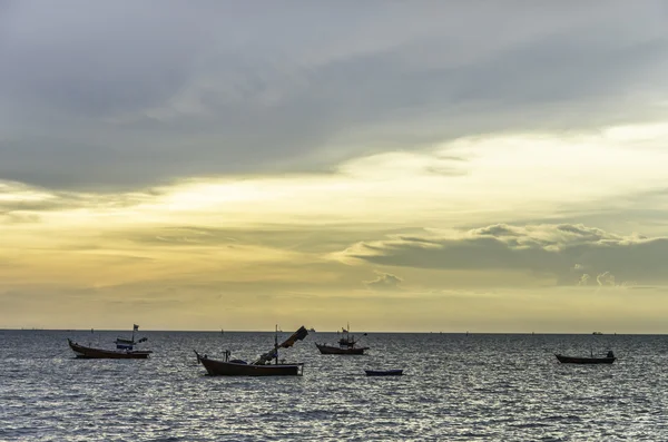 Fishing boat floating on sea with sunset sky