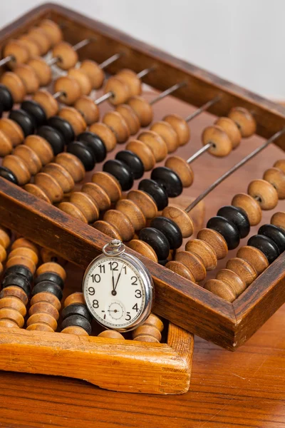 Pocket watch next to abacus