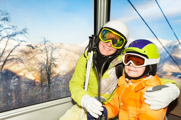 Mom and son skiers sit in cable car ski lift