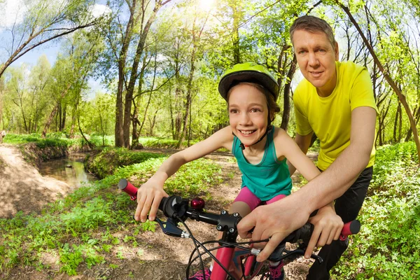 Father teaching his  daughter riding a bike