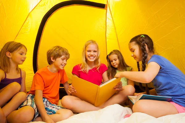 Five kids read books in tent