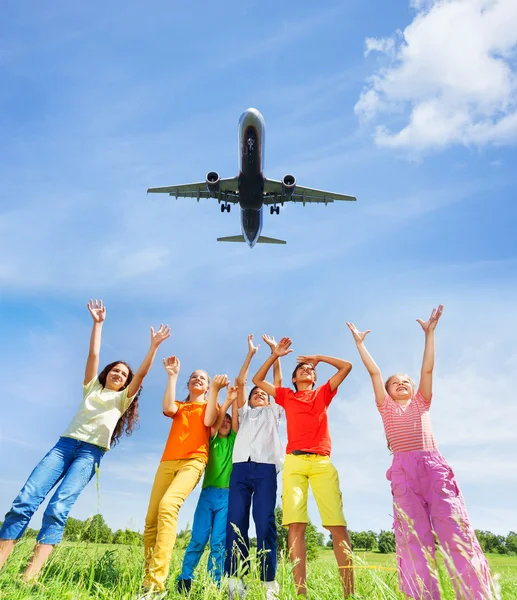 Children with hands up to plane
