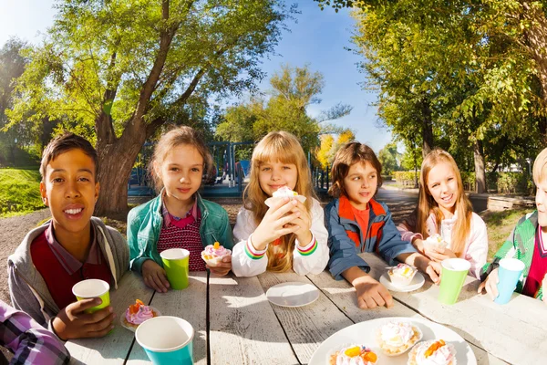 Children drink tea and eat cupcakes