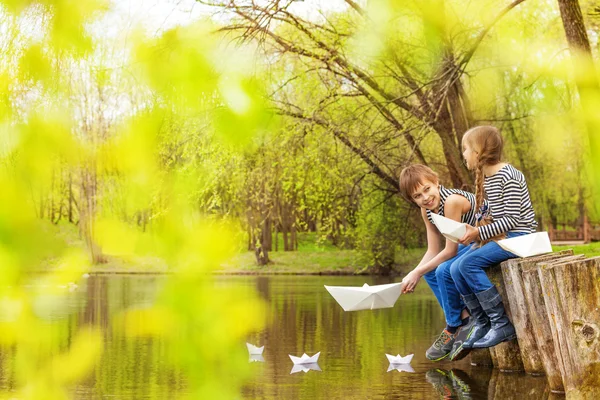 Boy and girl play with paper boats