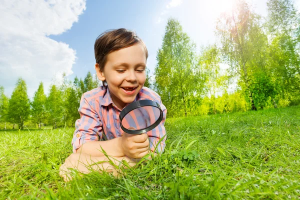 Happy small boy searches with magnifier
