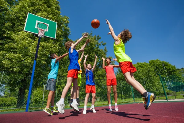 Teens in jump playing basketball game together