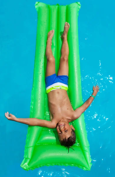 Boy relaxing on green inflatable mattress