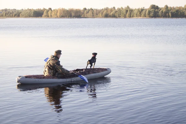 The hunter with an okhotnchy dog floats by the boat