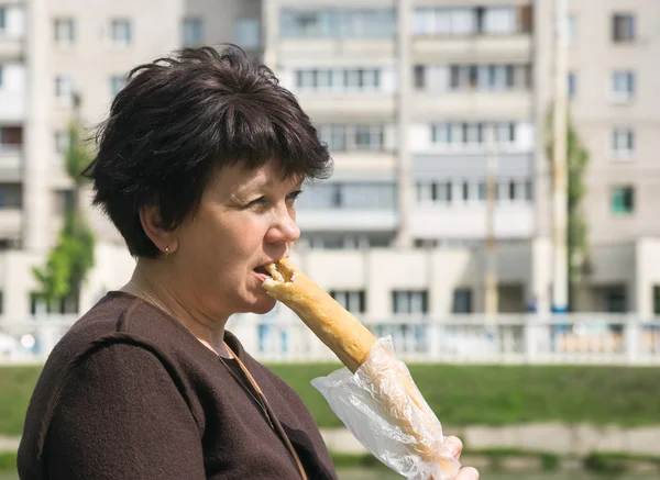 Woman eats long loaf in street