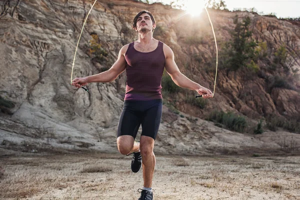Sporty man jumping rope outdoors