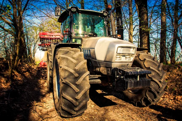 Closeup tractor on soil road in spring forest