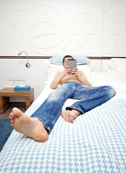 Image of a young adult strange man sitting on the bed in a hotel room