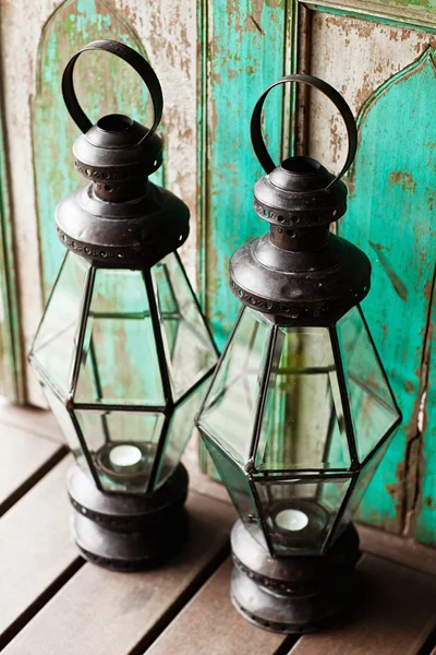 Old metal outdoor candle lamp stands on wood floor near mint woo