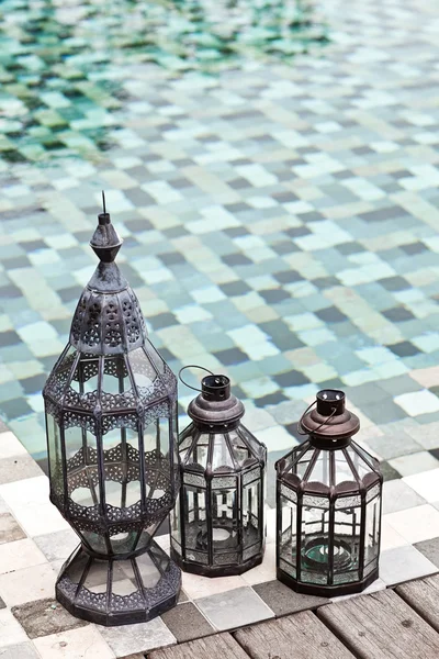 Vintage candle lamps standing near swimming pool. Summer in wint