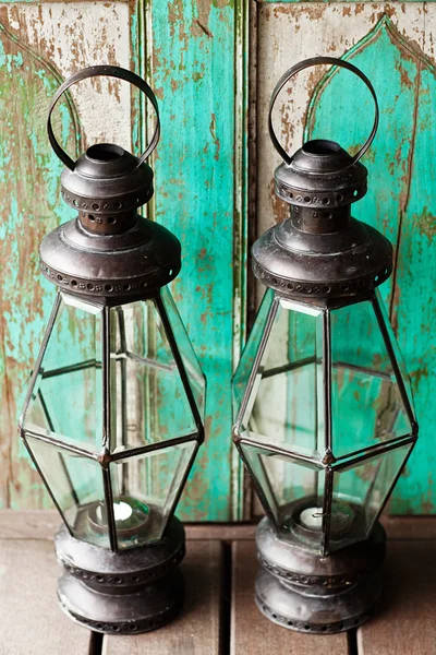 Old metal outdoor candle lamp stands on wood floor near mint woo