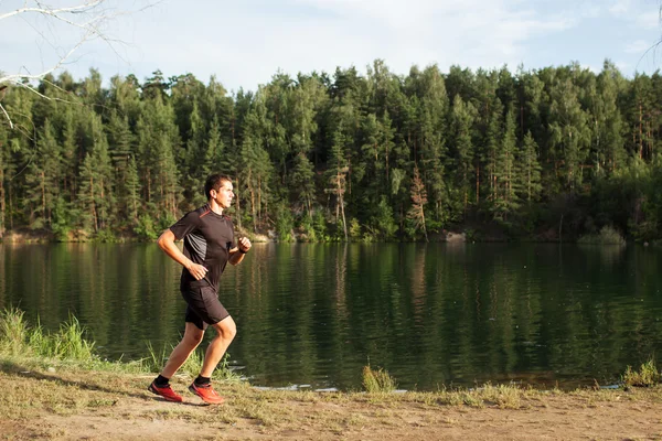 Male athlete runner running on road in forest