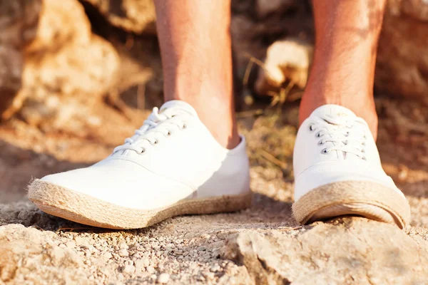 Man\'s legs in white tennis shoes on stone road