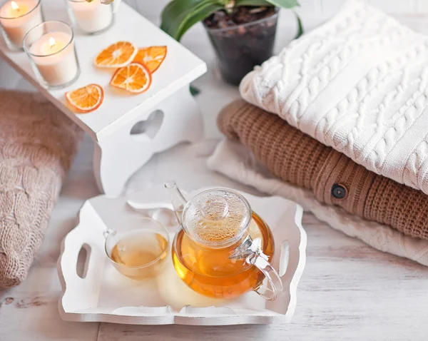 Tea-tray with hot grass drink, knitting clothes, dry oranges, ca