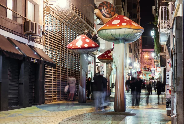 People walking on the street filled with giant mushrooms. Spain