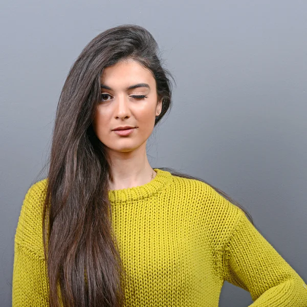 Portrait of woman winking against gray background