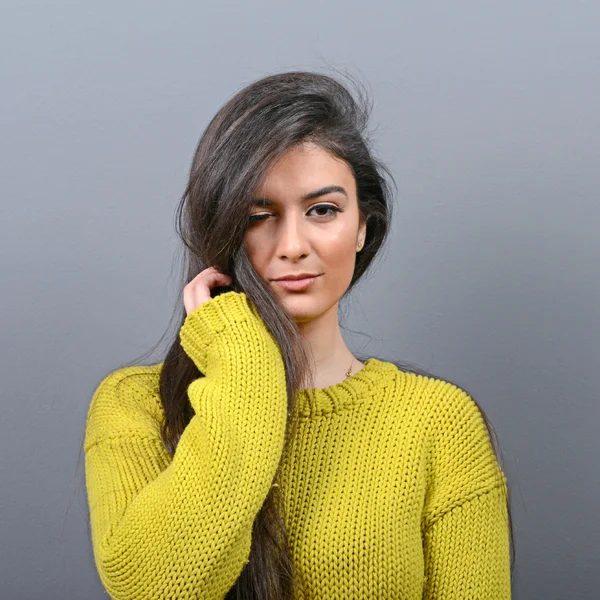 Portrait of woman winking against gray background