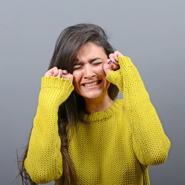 Woman crying and wiping tears against gray background