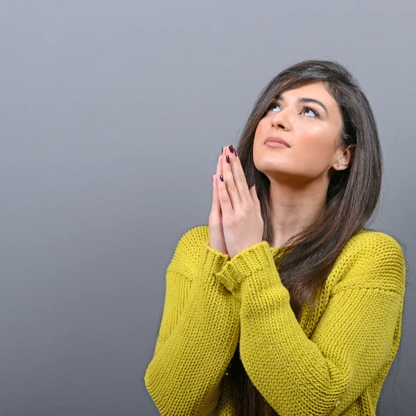 Woman praying about something or begging for mercy against gray