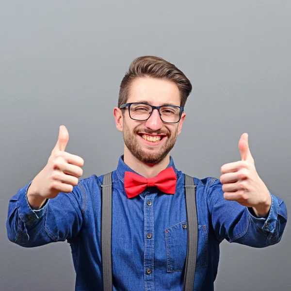 Portrait of a man showing thumb up or ok sign against gray backg