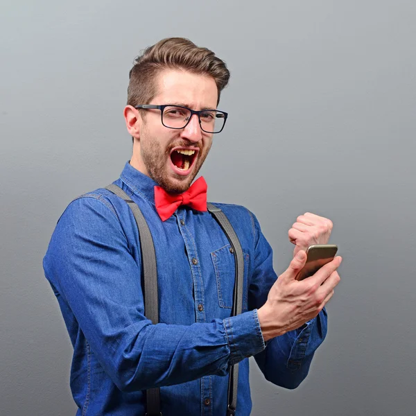 Portrait of ecstatic man holding cell phone and celebrating with
