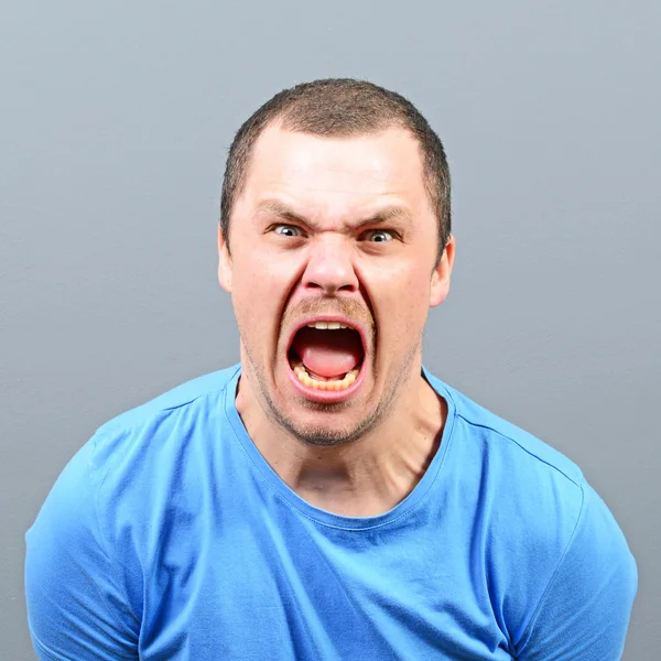 Portrait of a angry man screaming against gray background