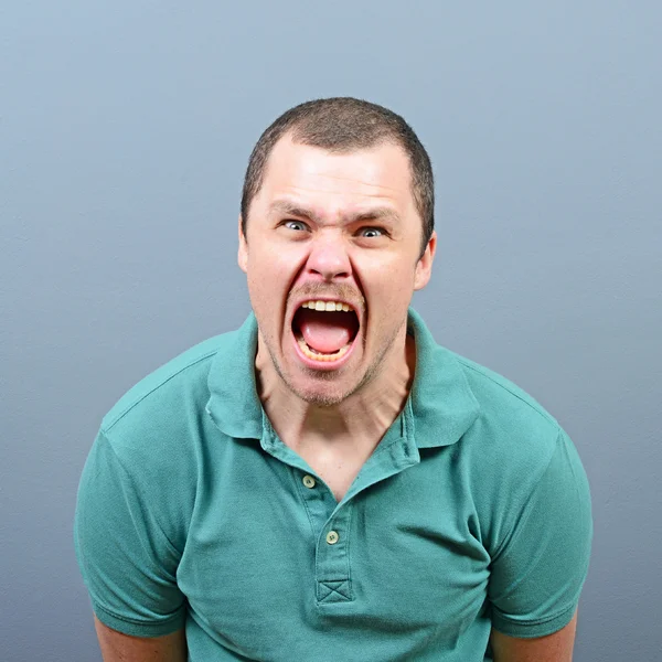 Portrait of a angry man screaming against gray background