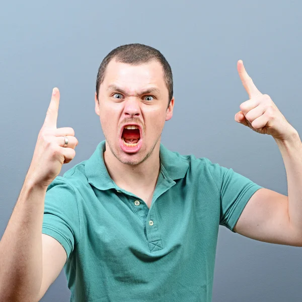 Portrait of a angry threatening man screaming against gray backg