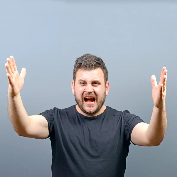 Portrait of a angry man screaming against gray background